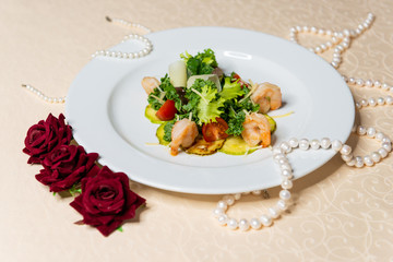 Salad of shrimp and vegetables on a white plate in the interiors of the restaurant.