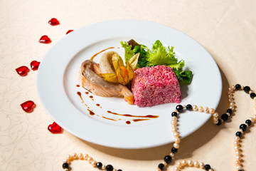 Restaurant dish of fish and beet salad in a white plate in the interior.