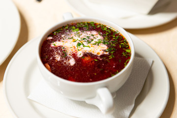 Red borsch with sour cream and dill in a white dish close-up. Restaurant menu.