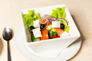 Greek salad in a white square dish closeup. Restaurant menu.