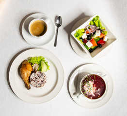 Set lunch from soup, salad, chicken and coffee on a white tablecloth top view. Business lunch.