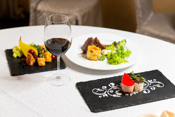 Dinner at a three-course restaurant with a glass of red wine. Complex lunch in the interior of the restaurant.