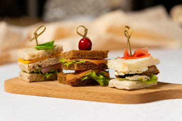 Three small sandwiches on a cutting board in the interiors of the restaurant. Cold appetizers.