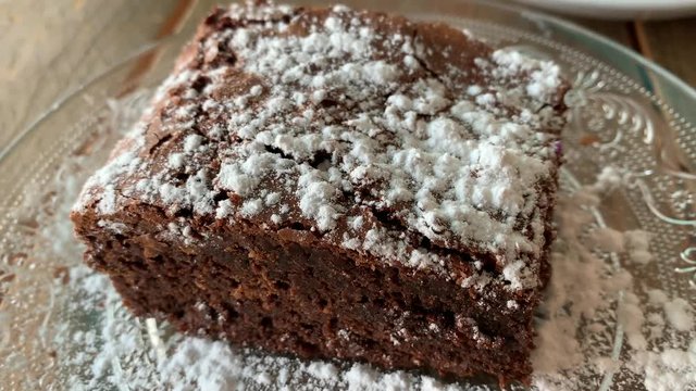 big brownie piece on a plate with powdered sugar on top.