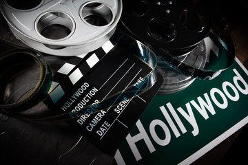 Multiple film reels and a clapboard on a wooden background. Film, Hollywood, entertainment industry objects - obrazy, fototapety, plakaty