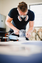 Woodworker using orbtail sander with epoxy table