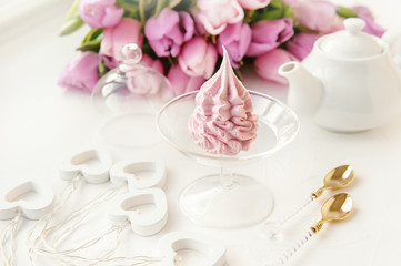 Fototapeta na wymiar Delicate pink apple marshmallow, made by hand against the backdrop of beautiful tulips.