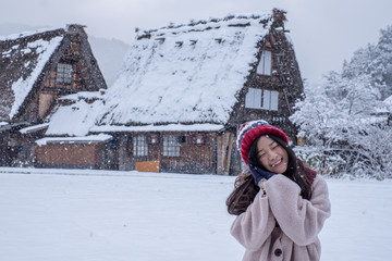 Shirakawa-go village in winter with Happy Asia Girl including copy space on traditional House Gassho style, one of UNESCO world heritage sites, Gifu, Japan. Background texture of traveling spectacular