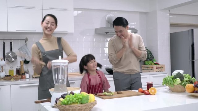 Asian family dancing together in kitchen at home. Daughter happy cheerful with father and mother. Concept of happy family and activity holiday.