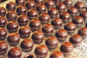 Dark chocolate candies are arranged in rows in special shapes. Cooking handmade chocolates. Selective focus.