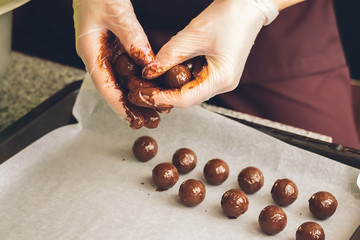 Making handmade chocolates. Round chocolates doused with liquid chocolate on the surface of the...