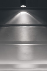 Obraz premium Gray plastered wall with a beam of light from the spotlight.