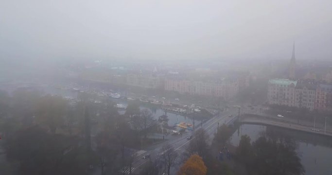 Moody aerial view Stockholm Sweden. Drone flies forward over misty Ostermalm. Wet foggy urban cityscape. Top down view, rainy streets.