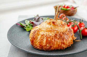 Chicken drumstick in dough baked in the oven with potatoes, tomatoes, onions and spices with a side dish of tomatoes and green salad © Oksana
