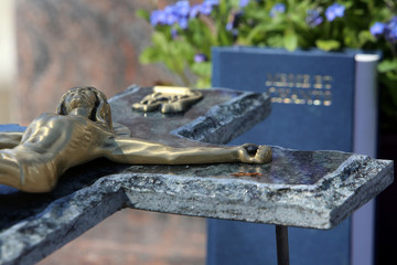 JŽsus-Christ sur la croix et livre de messe et chants sur une pierre tombale.