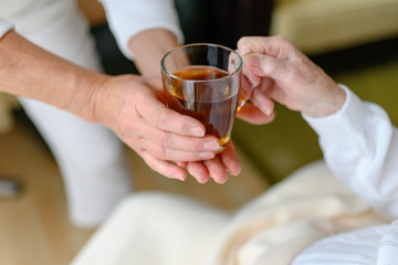 Rentnerin bekommt von der Pflegekraft ein Glas Tee gereicht