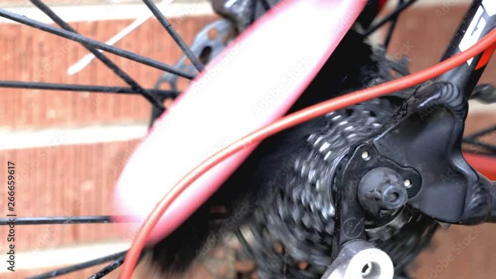Poster close up of a dirty rear cassette on a bicycle being scrubbed with a brush using water and degreaser