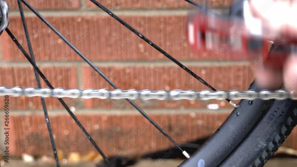Poster close up of a moving bicycle chain with lubricant as a part of routine maintenance. filmed in 4k.