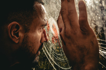 Obraz premium Victim of war. Wounded man victim looking through broken glass. Crime or violence victim. Victim of accident