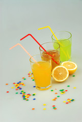 Three mason jar glasses of summer lemonade, and green, orange lemonade drinks, lemon, isolated on a gray background
