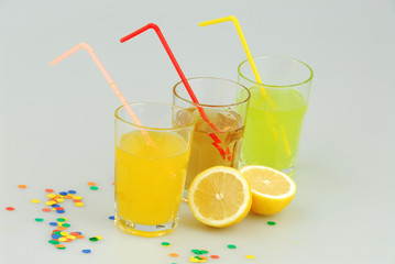 Three mason jar glasses of summer lemonade, and green, orange lemonade drinks, lemon, isolated on a gray background