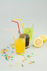 Three mason jar glasses of summer lemonade, and green, orange lemonade drinks, lemon, isolated on a gray background