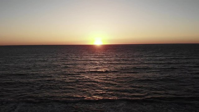 Red sun with sun road setting over sea in cyprus paphos. Sunset over ocean with sky and wavy sea.