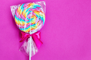 striped spiral multicolor Lollipop on pink background close up