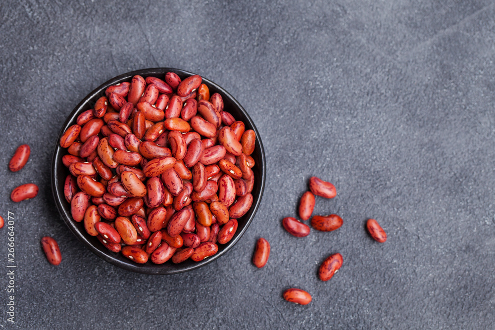 Wall mural Red lentil in a black bowl on grey stone background. Top view. Copy space.