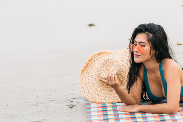 Thai woman in Bikini laying on beach point finger