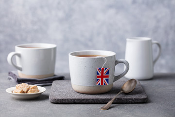 Tea in mugs with British flag tea bag label. Grey background. Copy space. © annapustynnikova