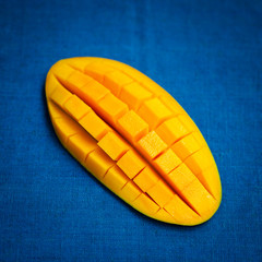 Fresh mango organic product on blue textile background. Close up.