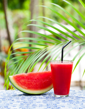 Watermelon fresh juice, smoothie on tropical outdoor background with palm leaves. Copy space.