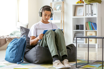 African-American teenage boy reading book at home © Pixel-Shot
