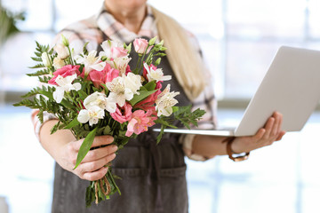 Florist with laptop and beautiful bouquet in shop