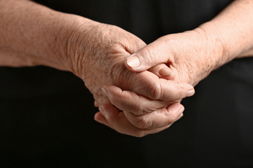 Fototapeta premium Hands of senior woman on dark background