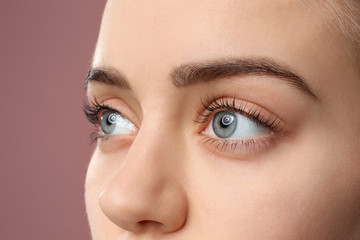 Beautiful young woman with laminated eyelashes on color background, closeup