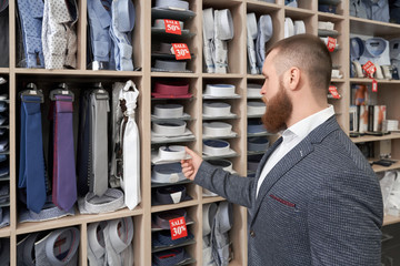 Bearded male client standing near racks with clothes