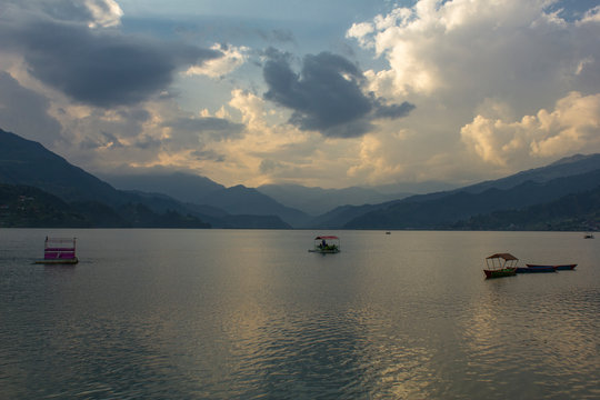 evening lake Phewa with catamarans on the background of a mountain valley in the fog and the evening sky