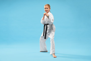 Happy girl in white kimono looking at camera while training