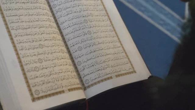 A bearded man reading Quran in a mosque.