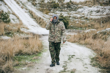 Soldier is standing in the camouflage uniform and checkered keffiyeh shemagh bandana. Terrorist is...