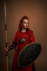 Female warrior keeping spear and shield and posing