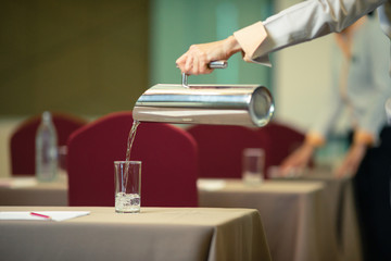 Hotel staff who are Pour drinking water into the glass in the seminar room.