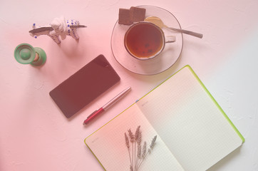 Workspace with notepad, cup of tea on a white background. Flat lay, top view office desk writing desk. Workplace freelancer. Copyspace. Coral tone