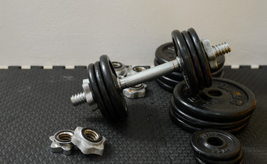 Naklejka na ściany i meble Iron dumbbells or weights on black floor in the gym. Weight Training Equipment. Health care concept.