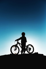Fototapeta na wymiar Silhouette of a little girl with a bicycle at sunset