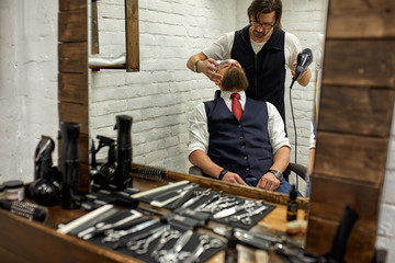 Stylish barber cuts a brutal man with a thick beard.