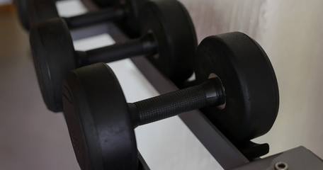 Rows of black dumbbell set on rack in the gym. Weight Training Equipment. Health care concept.
