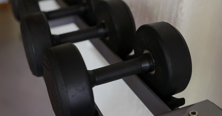 Obraz na płótnie Canvas Rows of black dumbbell set on rack in the gym. Weight Training Equipment. Health care concept.